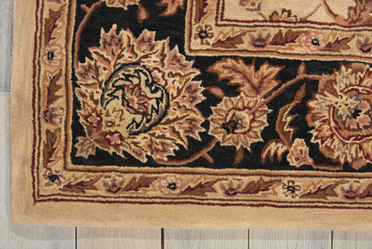 Close-up of an ornate oriental rug border with beige, gold, and black floral motifs on a dark background; fringe visible.