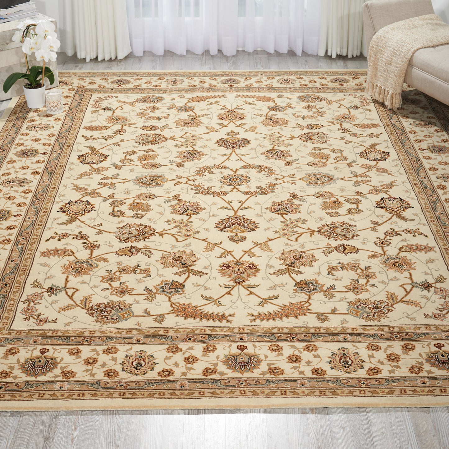 Cream Persian-style area rug with brown floral motifs and blue accents, bordered by an ornate beige frame in a living room.