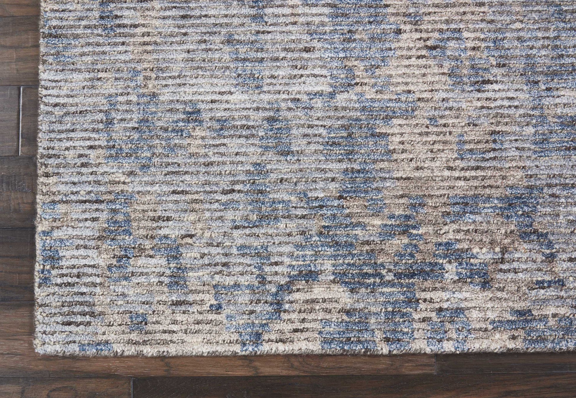 Blue and beige distressed area rug with subtle geometric pattern, rectangular woven texture on dark wood floor.