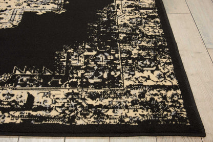 Rectangular black and cream distressed Oriental rug with ornate border, laid on light wood flooring.