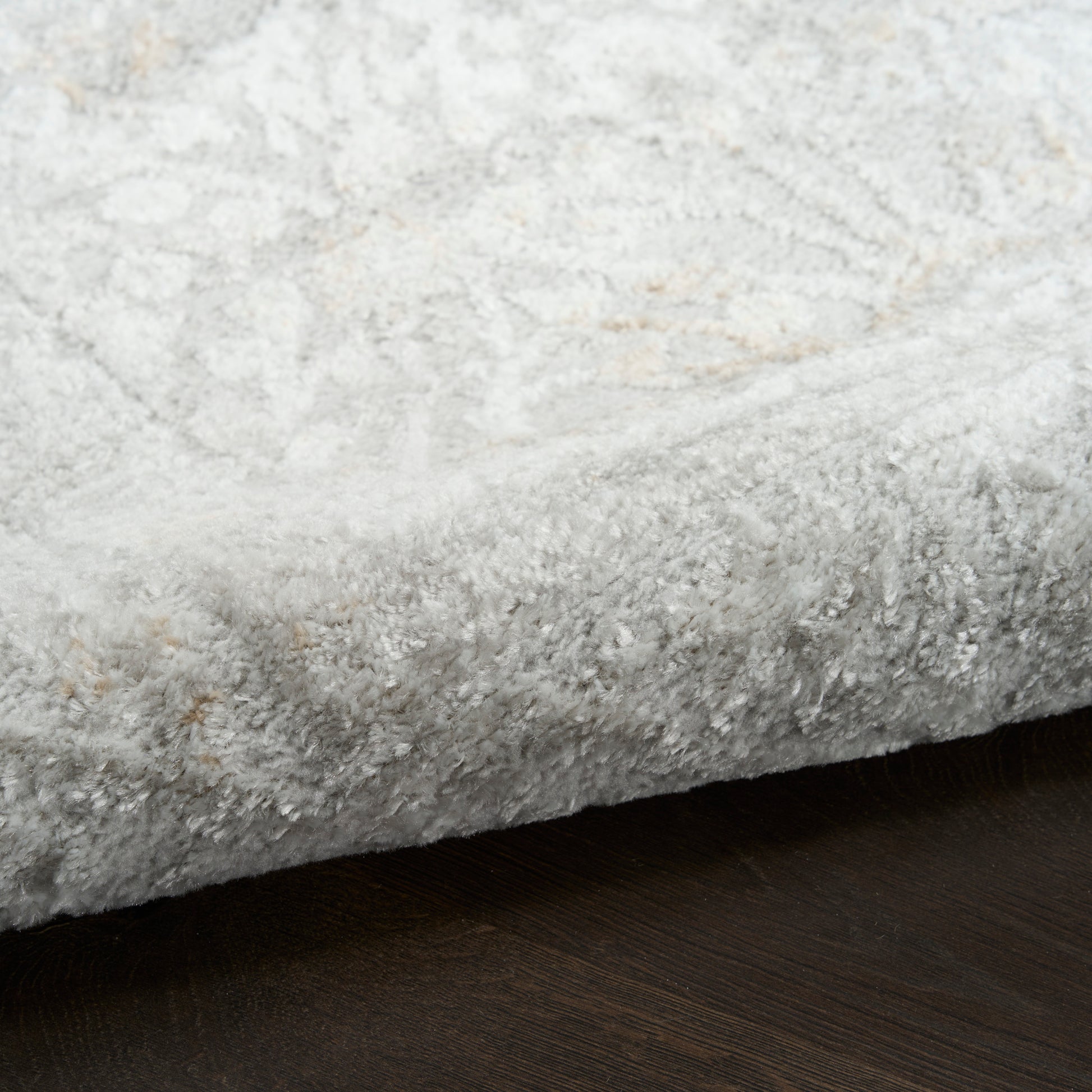 Light gray plush shag rug with a subtle cream pattern on a dark wood floor.