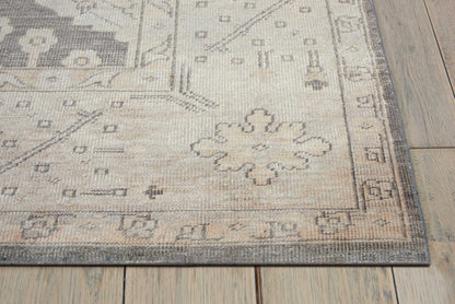 Beige-gray oriental-style area rug with subtle floral medallion pattern and decorative border on wooden floor.