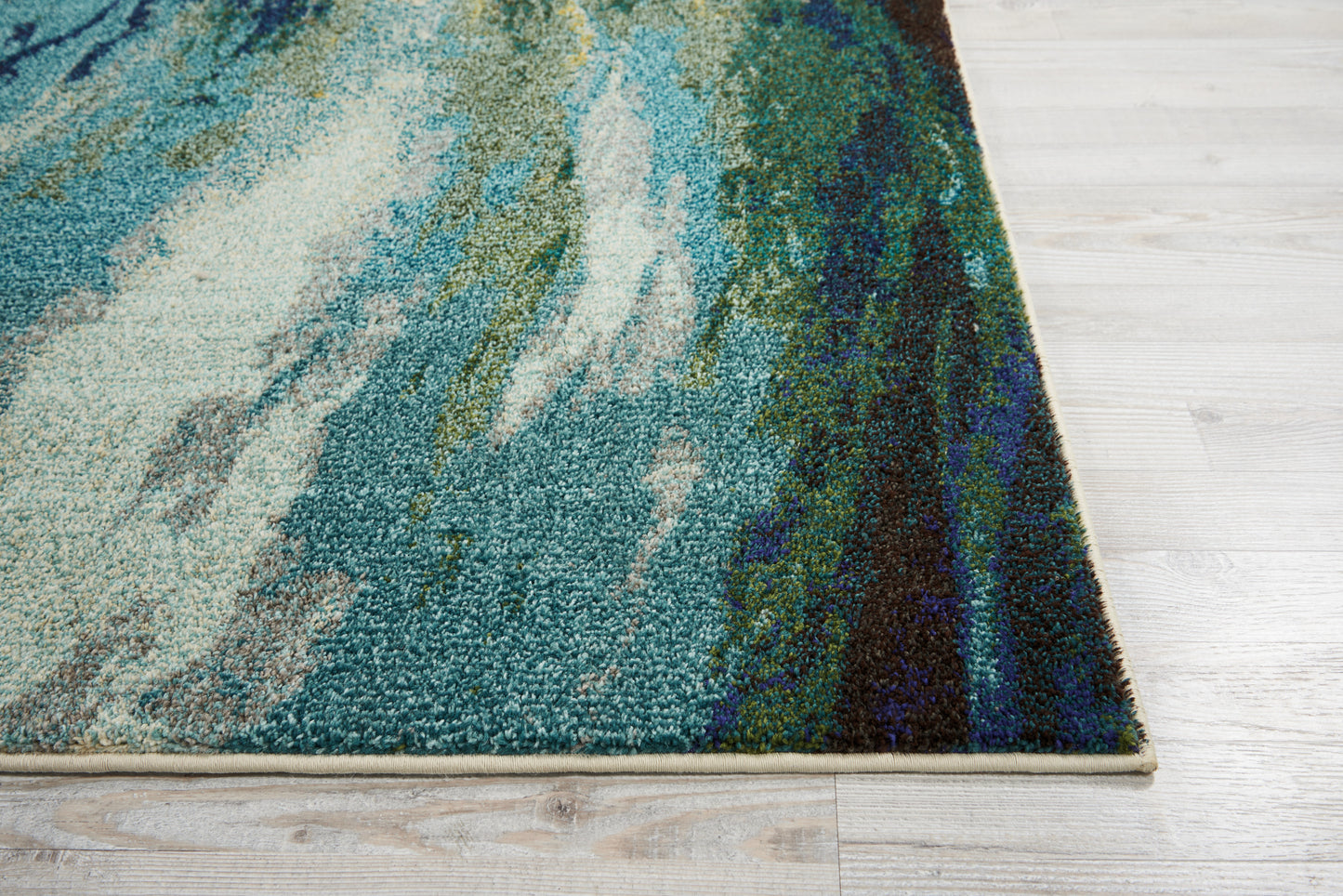 Rectangular textured abstract teal-blue and green rug on light wooden floor