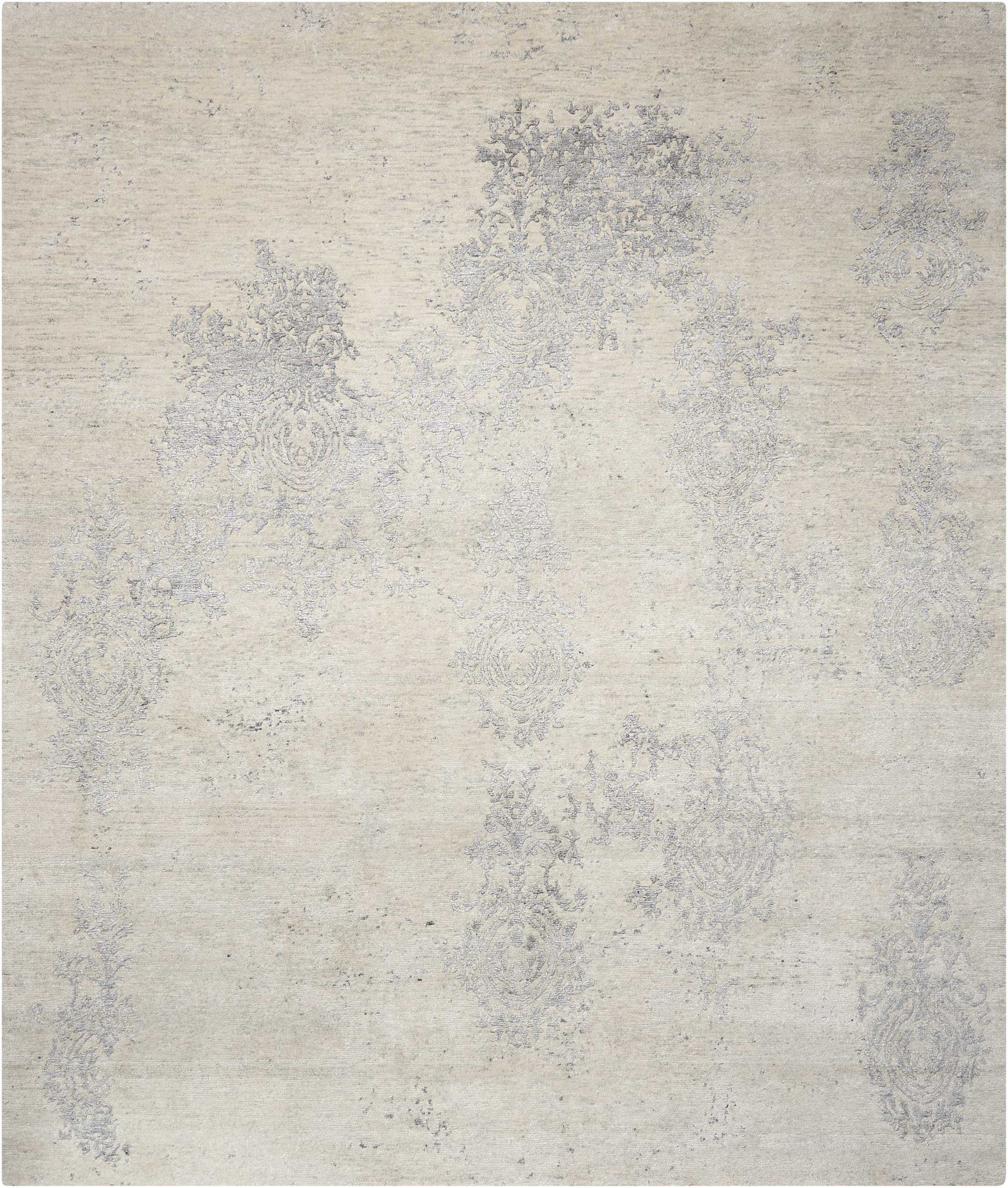 Beige distressed area rug with faded blue-gray damask pattern and vintage floral motifs.