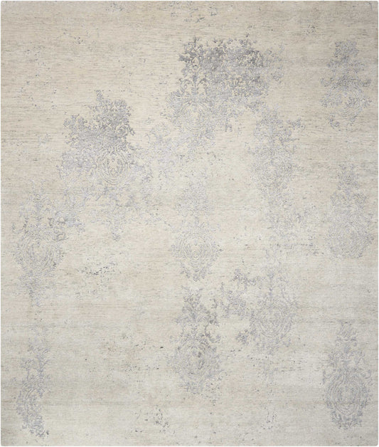 Beige distressed area rug with faded blue-gray damask pattern and vintage floral motifs.
