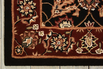 Traditional red Oriental rug with ivory and tan floral border laid on a light wooden floor.
