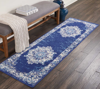 Blue distressed geometric runner rug on dark wood floor beside a wooden bench with gray cushion and beige knit throw.