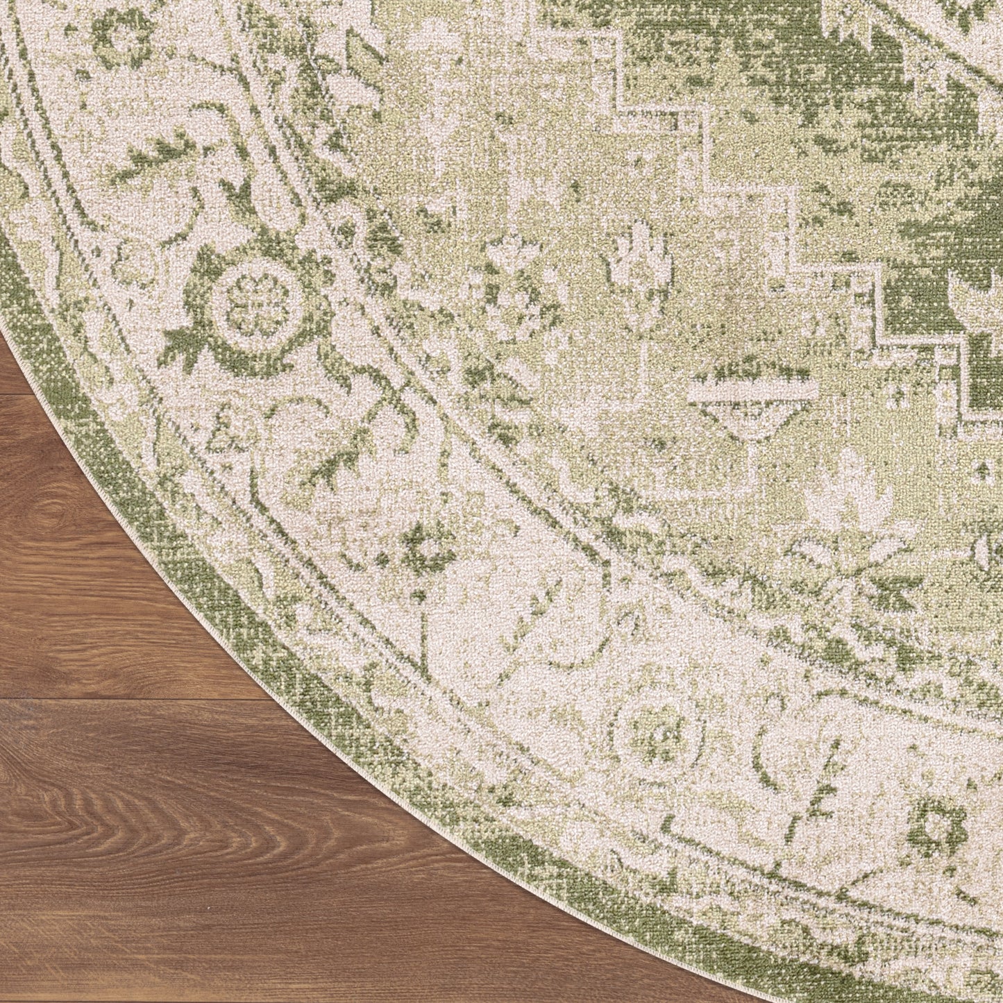 Round vintage oriental rug in sage green and ivory, floral border, on wooden floor.