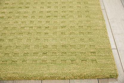 Olive-green textured loop-pile rug on light wood floor, edge visible.