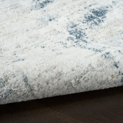 Close-up of a fluffy shag rug in white with a pale blue marbled pattern on dark wood floor.