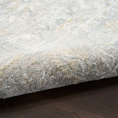 Soft gray-blue rug with subtle ivory abstract pattern and plush texture on dark wood floor.