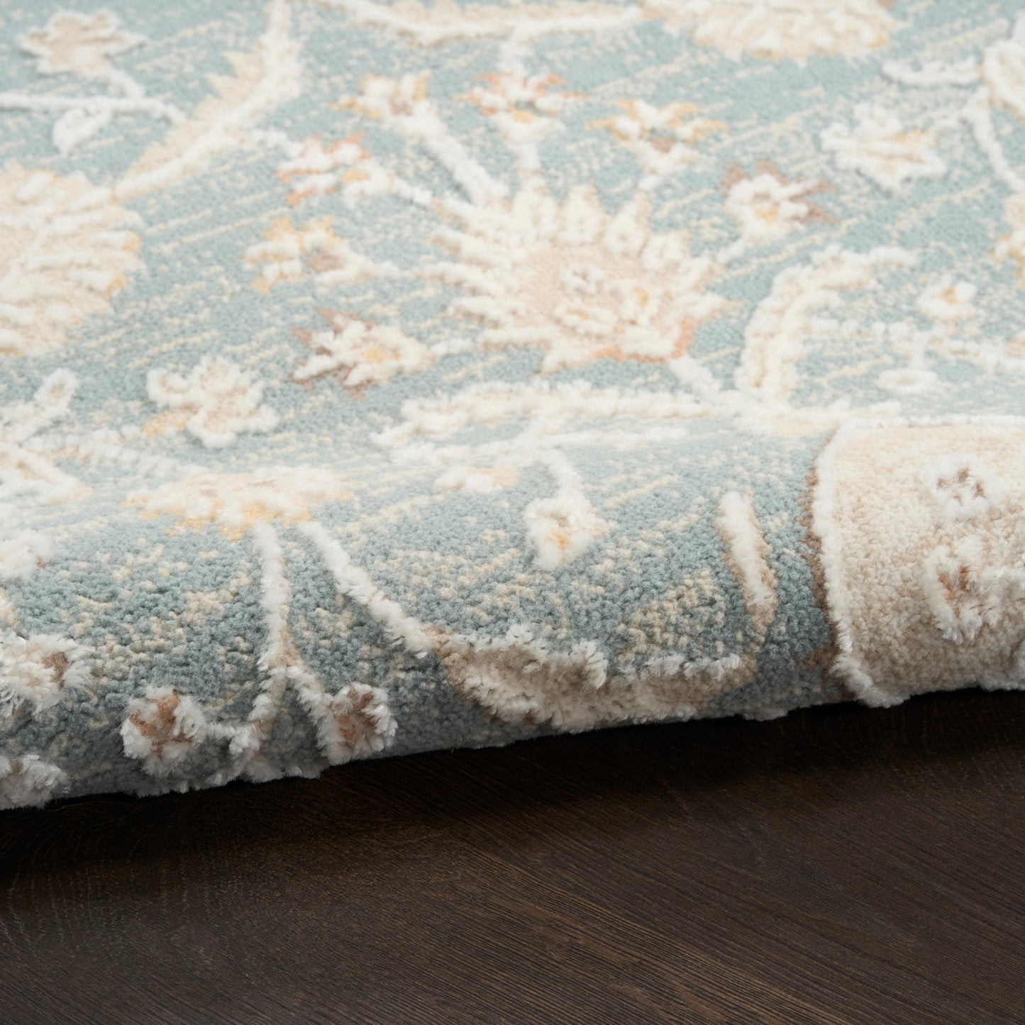 Blue and ivory floral area rug with plush tufted pile and rolled edge; pale teal base and cream blossoms.