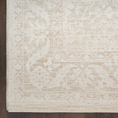 Rectangular cream-beige oriental-pattern area rug with fringe on dark wooden floor.