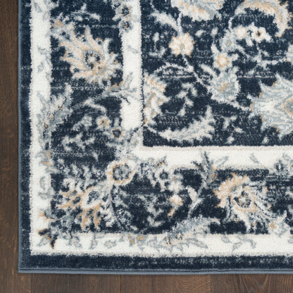 Navy blue oriental rug corner with ivory border and beige floral accents on a dark wood floor.