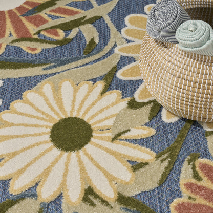 Close-up of a blue floral rug with a large white daisy, green stems; woven texture, round straw basket with rolled rugs.