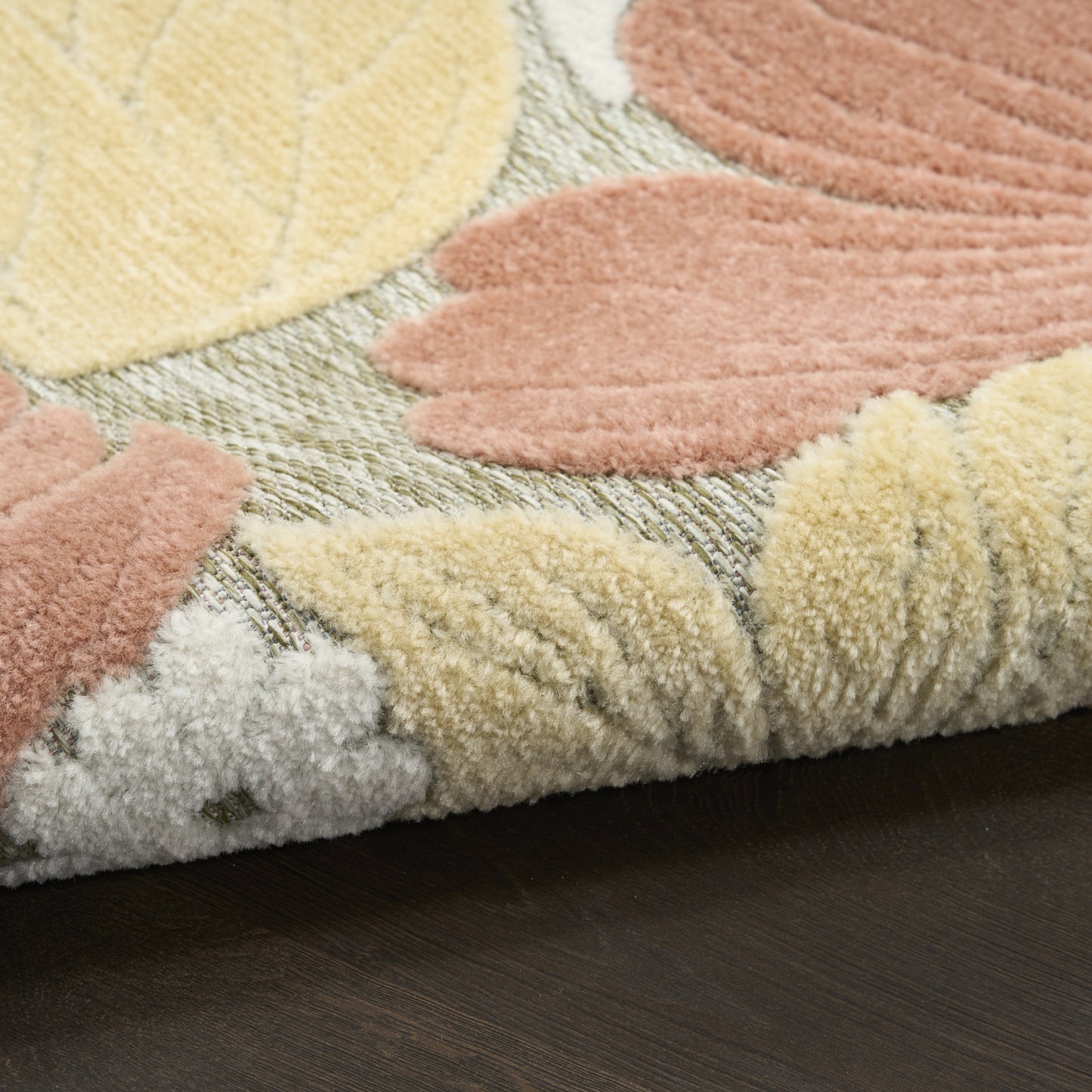 Pastel shag rug with leaf pattern in cream, blush pink and pale yellow on sage background; thick plush pile, rolled edge.