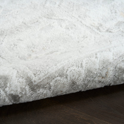Soft light gray shag rug close-up on dark wood floor; plush, thick pile, modern cozy style.