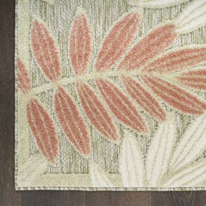 Beige woven rug with large coral-red leaf motifs, textured pattern, dark border edge, on a wooden floor.